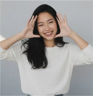 Half-body, front-facing, head slightly tilted left, eyes looking at the camera, broad smile; both hands raised near face with fingers spread; shoulders relaxed, torso straight; eye-level camera angle, medium crop.